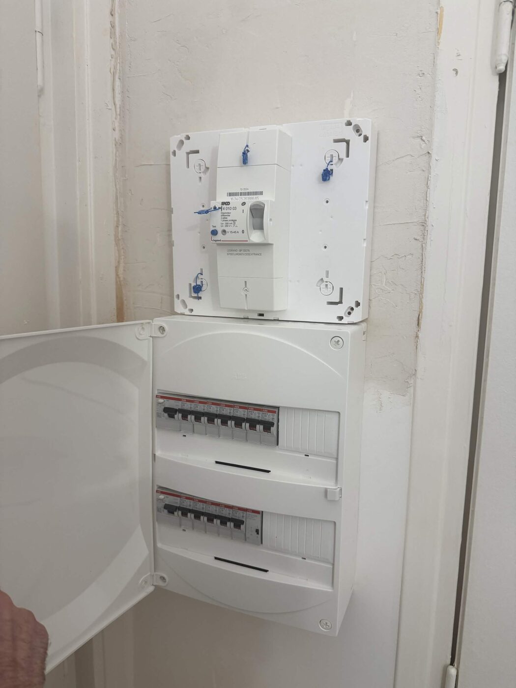 Tableau électrique terminé, porte ouverte, avec les deux rangées de disjoncteurs et interrupteurs différentiels installés