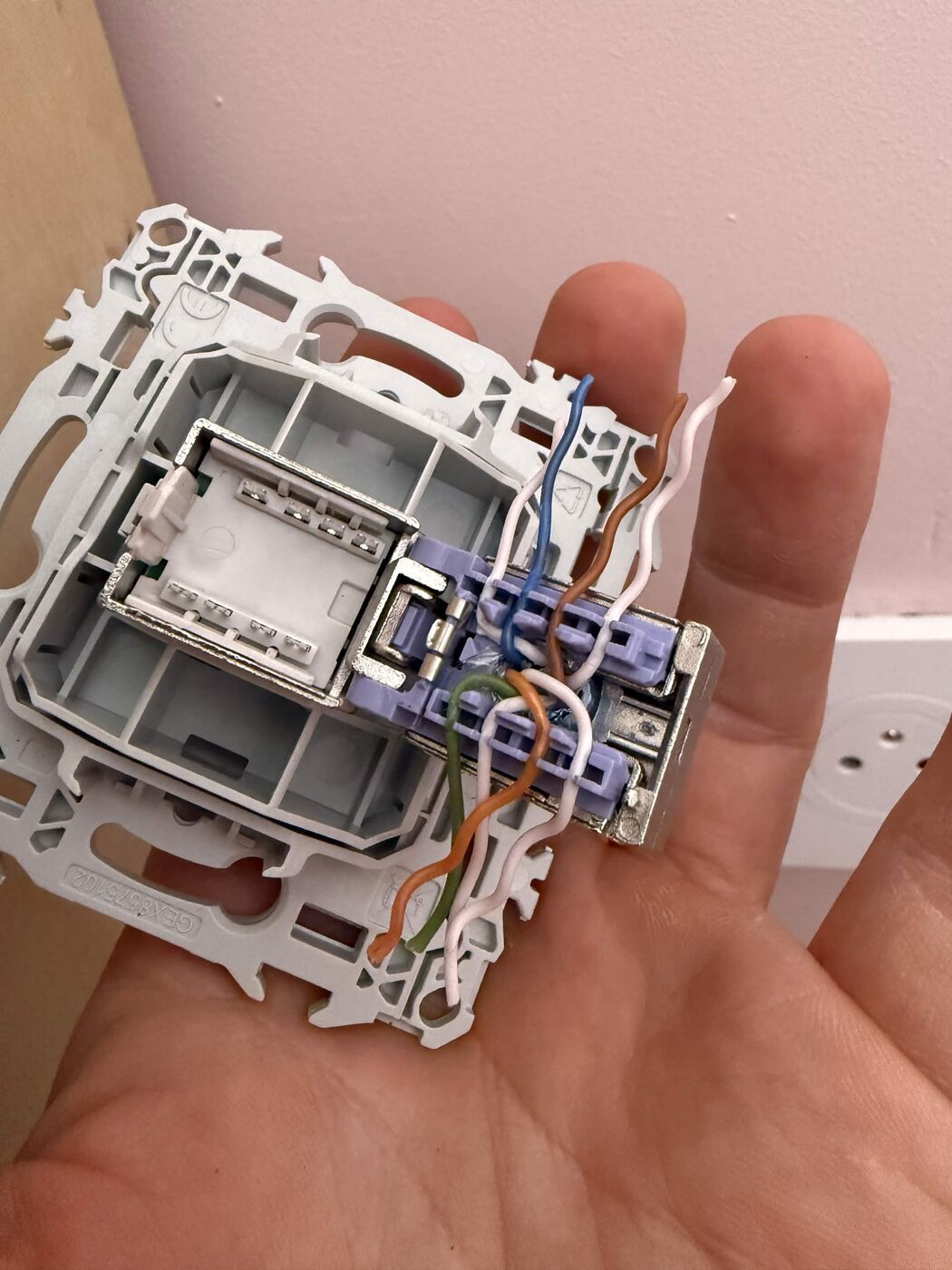Connecting a Category 6 internet cable to an RJ45 wall socket, wires stripped and crimped onto the connector